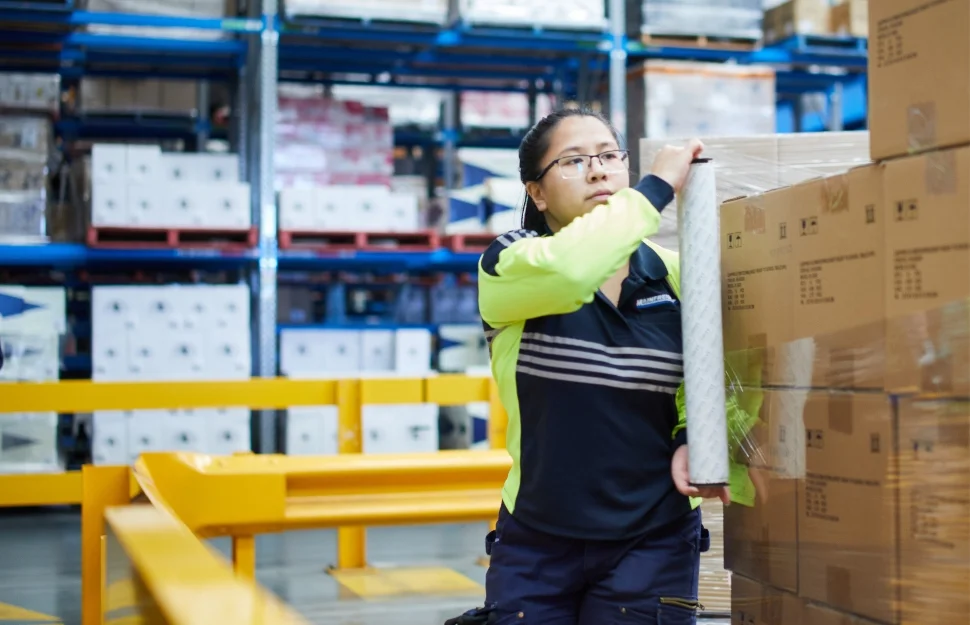 Mainfreight Global Supply Chain Logistics Services - Mainfreight Supply Chain Logistics Services. Female team member wrapping pallet in warehouse.
